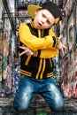 The little boy in the style of Hip-Hop . Children`s fashion.Cap and jacket. The Young Rapper.Graffiti on the walls.Cool rap dj. Royalty Free Stock Photo