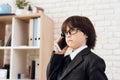 A little boy in glasses and suit presents himself as a businessman. The dark-haired boy plays a rich man. Royalty Free Stock Photo