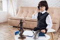 A little boy in a suit is talking on the phone. On the table is a statuette of the femida.