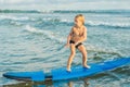 Little boy surfing on tropical beach. Child on surf board on ocean wave. Active water sports for kids. Kid swimming with