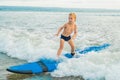 Little boy surfing on tropical beach. Child on surf board on ocean wave. Active water sports for kids. Kid swimming with