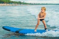 Little boy surfing on tropical beach. Child on surf board on ocean wave. Active water sports for kids. Kid swimming with