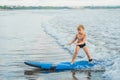 Little boy surfing on tropical beach. Child on surf board on ocean wave. Active water sports for kids. Kid swimming with