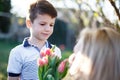 Little boy surprise mother with tulips outdoor closeup