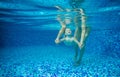 Little boy swimming underwater, mother or instructor holding him