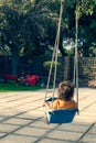 Little boy on swing facing a playground