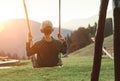 Little Boy swinging on the mountain kids park playground in the evening sunset rays. Careless childhood concept image