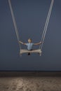 Little boy swinging on rope swing on the beach at twilight. back view. Dark magical sky. Child in the sky