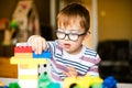 little boy with syndrome dawn in the glasses playing with colour blocks