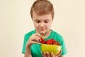 Little boy takes strawberry from the bowl