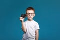 Little boy taking a picture using a retro camera. Child boy with vintage photo camera isolated on blue background. Old Royalty Free Stock Photo