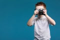 Little boy taking a picture using a retro camera. Child boy with vintage photo camera isolated on blue background. Old Royalty Free Stock Photo