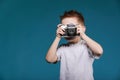 Little boy taking a picture using a retro camera. Child boy with vintage photo camera isolated on blue background. Old Royalty Free Stock Photo