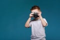 Little boy taking a picture using a retro camera. Child boy with vintage photo camera isolated on blue background. Old Royalty Free Stock Photo