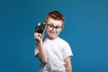 Little boy taking a picture using a retro camera. Child boy with vintage photo camera isolated on blue background. Old Royalty Free Stock Photo