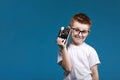 Little boy taking a picture using a retro camera. Child boy with vintage photo camera isolated on blue background. Old Royalty Free Stock Photo