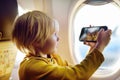 Little boy is taking a shot view of airfield from illuminator plane by smartphone Royalty Free Stock Photo