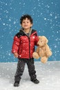 Little boy with teddy bear in the snow