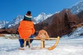 Little boy with teddy rabbit sit on wooden sledge back view Royalty Free Stock Photo