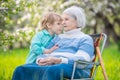 Little boy telling a secret to his great grandmother in orchard