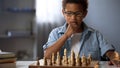 Little boy thinking on chess move, intelligent hobby, logic development, leisure Royalty Free Stock Photo