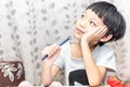 Little boy thinking about somthing and looking up, confused about an idea. Small child hand holding pencil