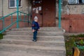 A little boy of three or four years with blond hair on the porch of an apartment building in a provincial town