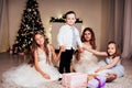The little boy and three girls kids open Christmas presents new year winter Christmas tree Royalty Free Stock Photo