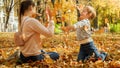 Little boy throwing fallen autumn leaves at his mother at park