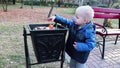 A little boy throws garbage in the trash in the street. The concept of waste management and environmental protection. Proper paren