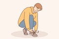 A little boy ties a shoelace on his shoe