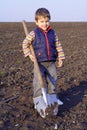 Little boy to dig on field with big shovel Royalty Free Stock Photo