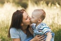 Little boy todler kisses his mother in nature in the summer