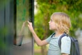 Little boy tourist studying at the big public outdoor street map of city. Child is interested in a visual map or advertising Royalty Free Stock Photo