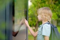 Little boy tourist studying at the big public outdoor street map of city. Child is interested in a visual map or advertising Royalty Free Stock Photo