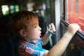 Little boy with toy looking out of train window Royalty Free Stock Photo