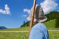 Little boy with traditional hat and wooden stick helping to herd cows in Austrian Alps. Vorarlberg, Austria.