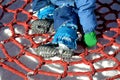 Little boy trains stability at the children`s rope center, playground for schoolchildren. A very torn net must be repaired or repl Royalty Free Stock Photo