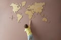 Little boy trying to get hold of a wooden world map on the wall Royalty Free Stock Photo