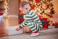 Little boy trying to open Christmas giftbox indoors. Royalty Free Stock Photo