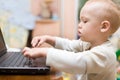 Little boy typing text on laptop at home