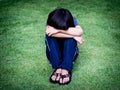 Little boy unhappy sad and sitting alone on the grass field Royalty Free Stock Photo