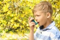 Little boy using inhaler near blooming tree. Allergy concept Royalty Free Stock Photo