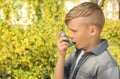 Little boy using inhaler near blooming tree. Allergy concept Royalty Free Stock Photo
