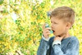 Little boy using inhaler near blooming tree. Allergy concept Royalty Free Stock Photo