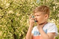 Little boy using inhaler near blooming tree. Allergy concept Royalty Free Stock Photo