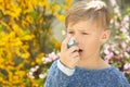 Little boy using inhaler near blooming tree. Allergy concept Royalty Free Stock Photo