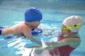 Little boy using the kickboard for learning to swim with trainer in the swimming pool Royalty Free Stock Photo