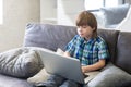 Little boy using laptop on a sofa at home Royalty Free Stock Photo