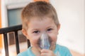 Little boy making inhalation with nebulizer at home. Close up portrait of boy